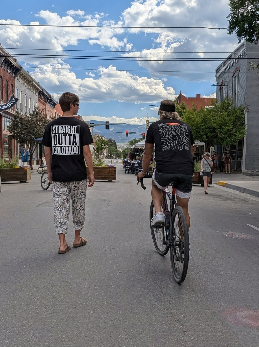 Man walking down a Salida street wearing the black Straight Outta Colorado Tee, back print