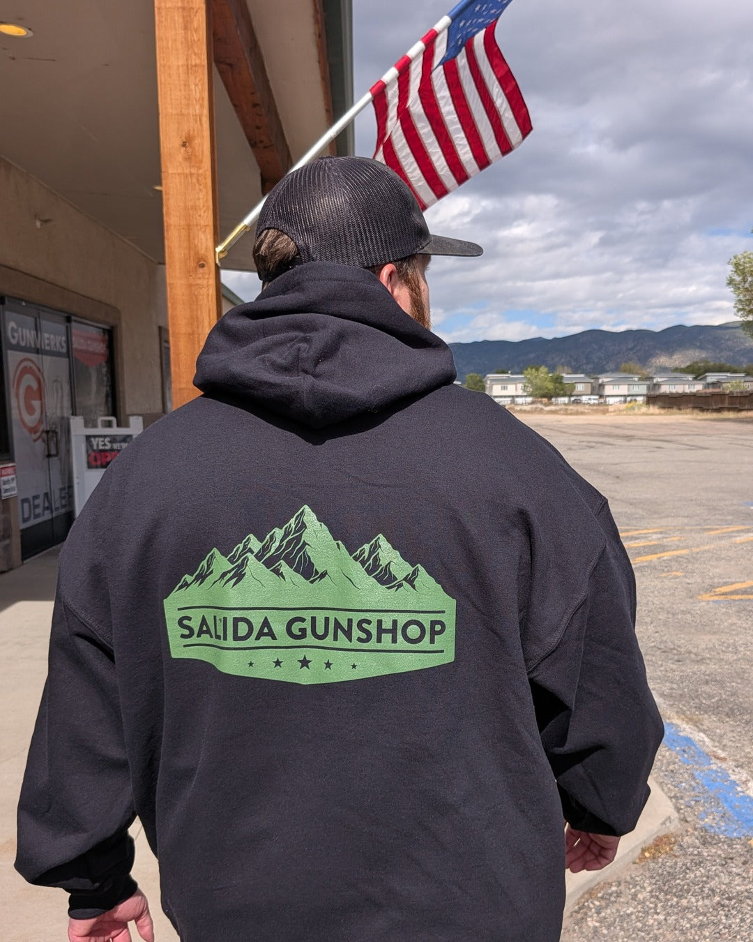 Back of Salida Gunshop Mountain Logo Hoodie worn outside the shop under the American flag
